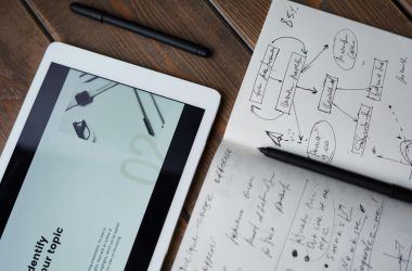 Digital and handwritten brainstorming tools on a wooden desk, ideal for business and study contexts.